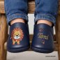 Preview: KI generierte Vorschaubild wie es aussieht an Babyfüßen. Handgemachte Lederpuschen in dunkelblau mit Stickerei Löwe steht, Namen und Tatzen für Babys