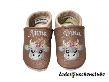 Lederpuschen cappuccino-beige mit beiderseits Namen am Spann (creme) und beiderseits Stickerei Boho Kuh (steingrau-grau, Blume rosa-altrosa, hellgrün)
