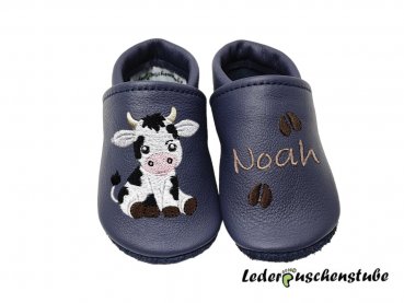 Personalisierte Krabbelschuhe in dunkelblau mit Namen (cappuccino), süßem Kuh-Motiv und gestickten Hufabdrücken (dunkelbraun) von Lederpuschenstube.