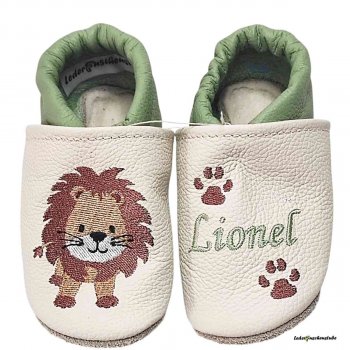 Krabbelschuhe in creme-pistazie, rechts Löwe steht (hellbraun-rotbrau-weiß-schwarz) und links Name (pistazie) mit 2 Tatzen (rotbraun)