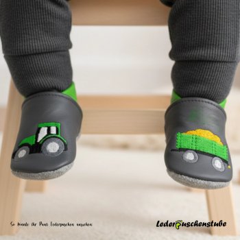 Designbeispiel an Baby Füßen: Lederpuschen anthrazit-mittelgrün, Stickerei Traktor Anhängerladung (mittelgrün-grau)