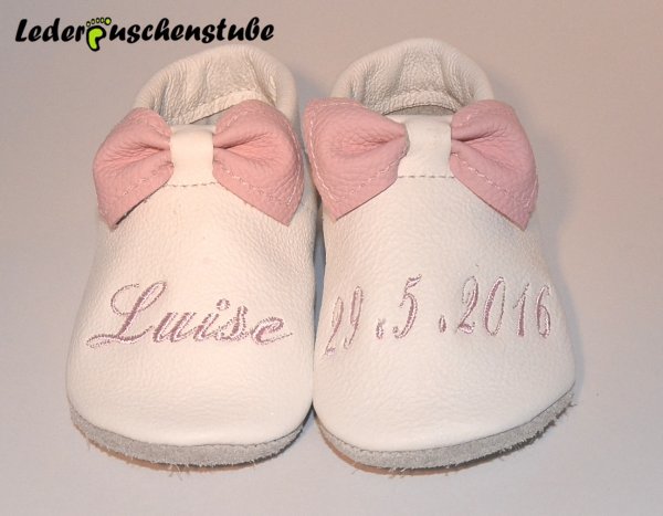 Lederpuschen-als-Taufschuh-in-weiss-Schleife-rosa-rechts-mittig-den-Namen-u.-links-das-Geburts--o.-Taufdatum