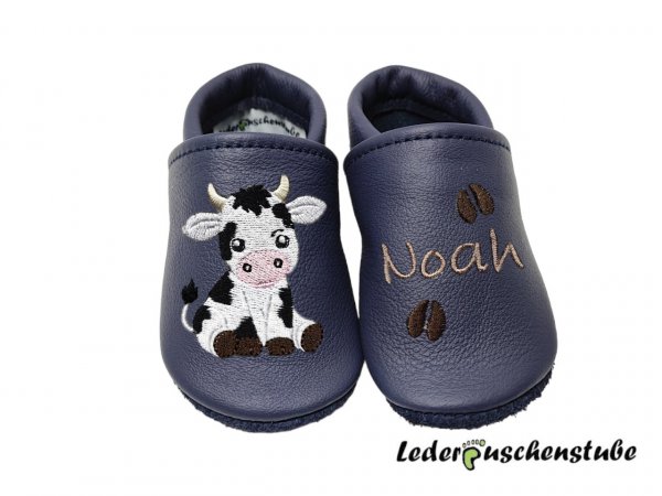 Personalisierte Krabbelschuhe in dunkelblau mit Namen (cappuccino), süßem Kuh-Motiv und gestickten Hufabdrücken (dunkelbraun) von Lederpuschenstube.