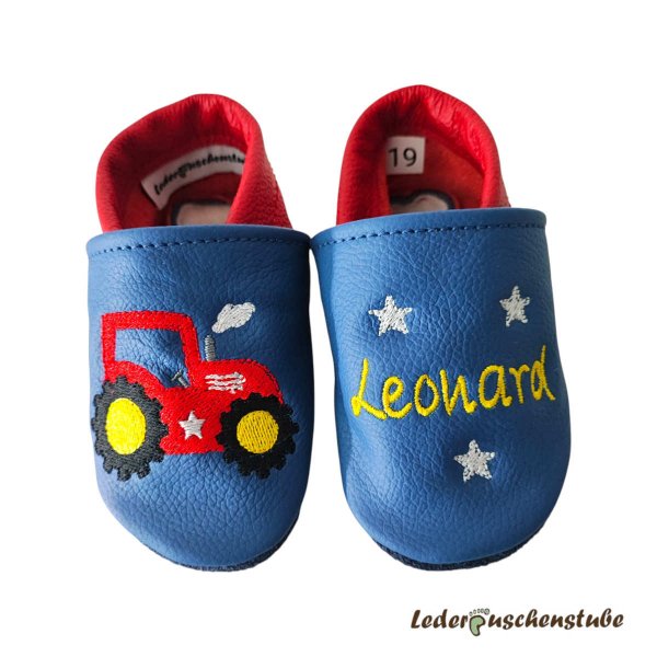 Lederpuschen Baby mit Namen – Lederpuschen in jeansblau-rot, mit rechts Traktor (rot-gelb-schwarz-weiß-steingrau-weiß), links Name (gelb) mit 3 Sterne (weiß)