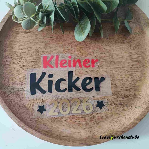 Hier habe ich das fertig geschnittene Motiv Kleiner Kicker 2026 auf einen Holzteller zusammengelegt.