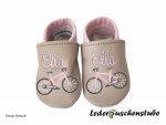 Designbeispiel von einem Paar Krabbelschuhe beige-rosa mit beiderseits Namen rosa am Spann und beiderseits Stickerei Fahrrad (Rahmen in rosa)